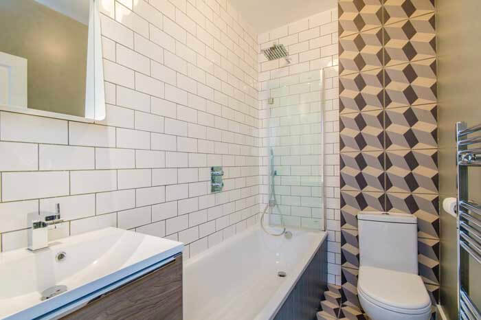 Islington bathroom renovation – subway tiled walls, patterned feature wall, and modern bath at Loraine Rd N7 project