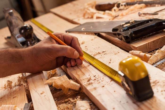 Islington Carpentry & Joinery – craftsman measuring timber with tape and pencil for bespoke woodwork