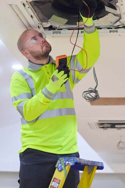 Electrician installing a ventilation unit, showing electrical and ventilation services in Islington.